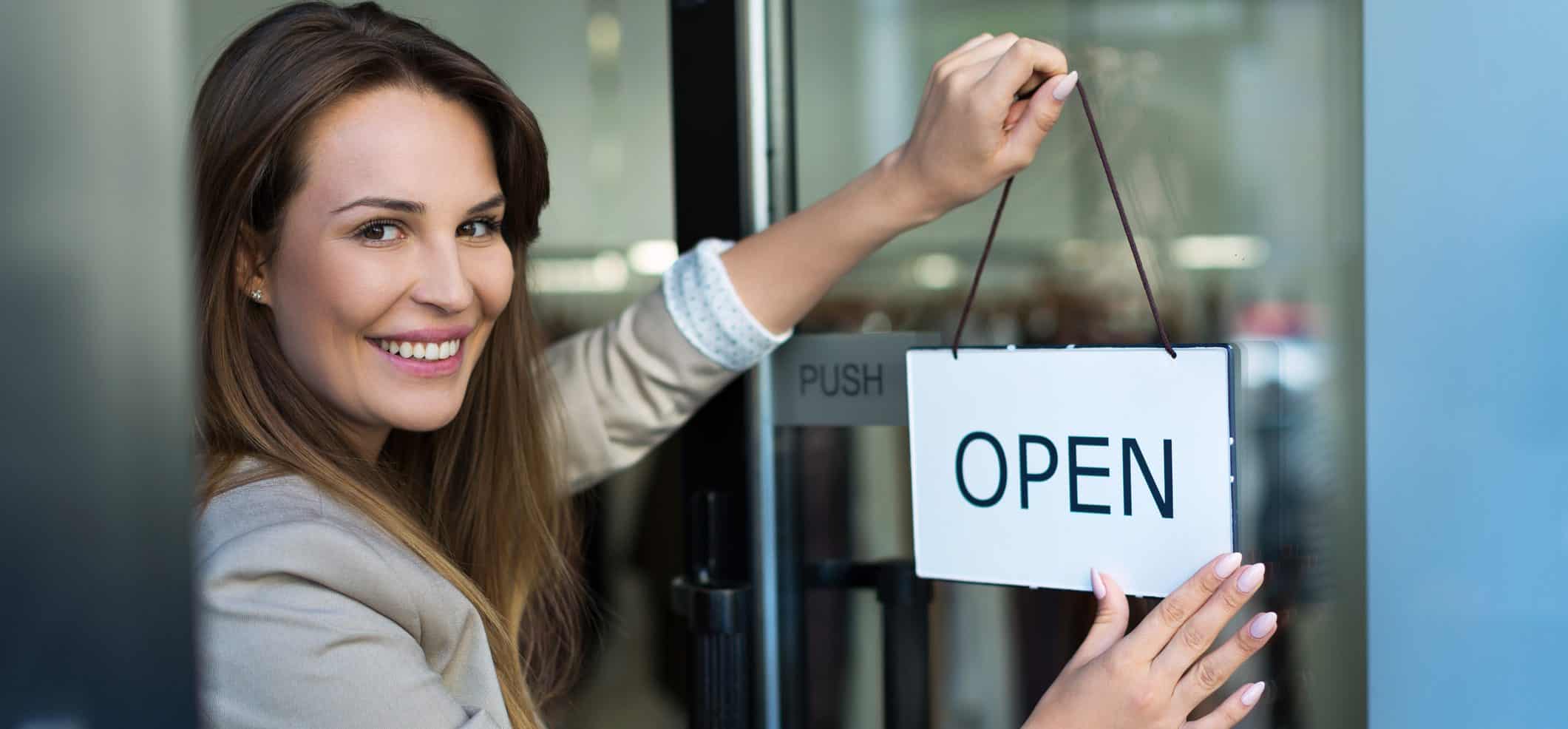 Woman hanging open sign on door